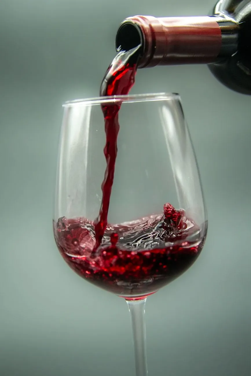 Red wine being poured into a glass against a grey background