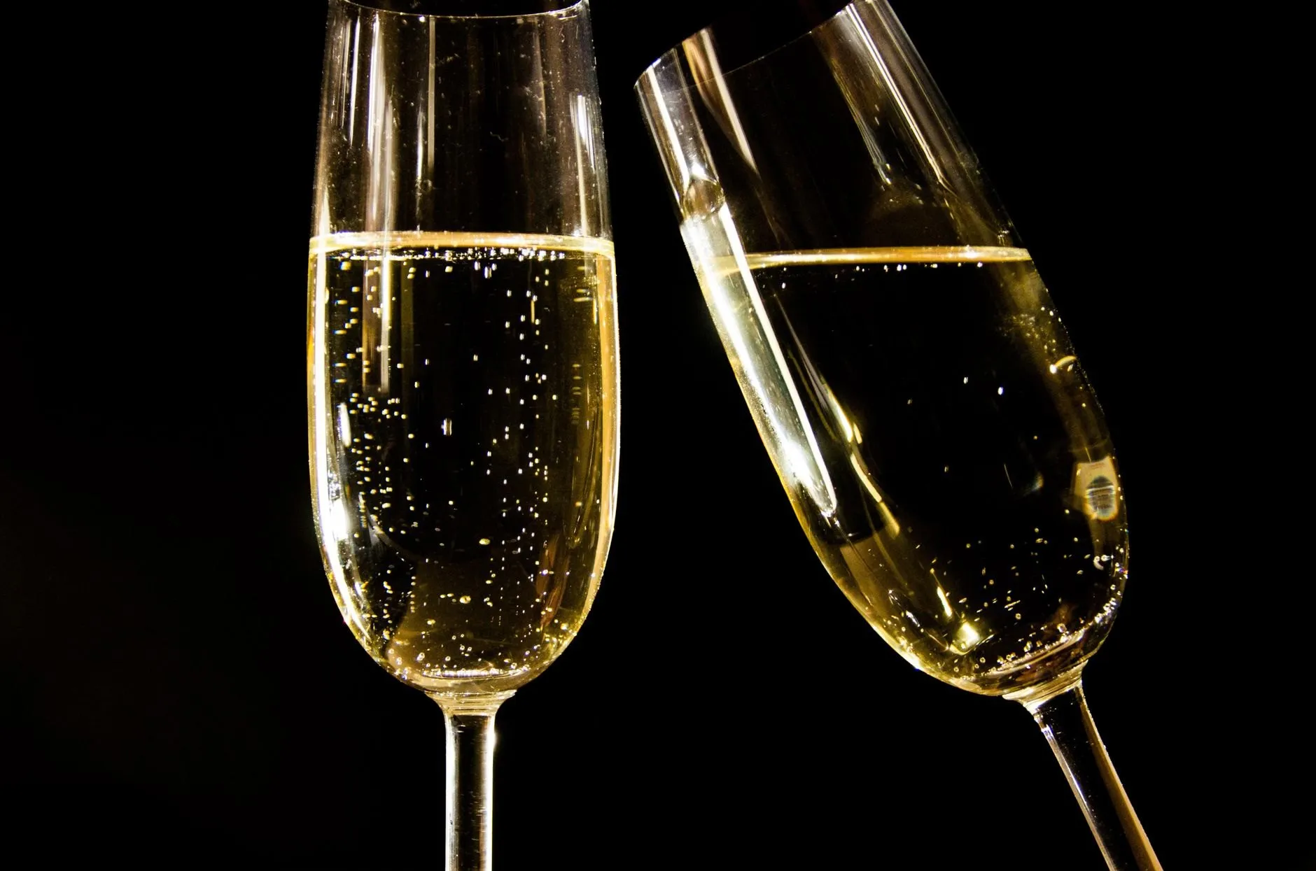 Two flutes of golden sparkling wine against a black background